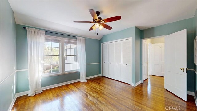 unfurnished bedroom with ceiling fan, wood-type flooring, a closet, and lofted ceiling