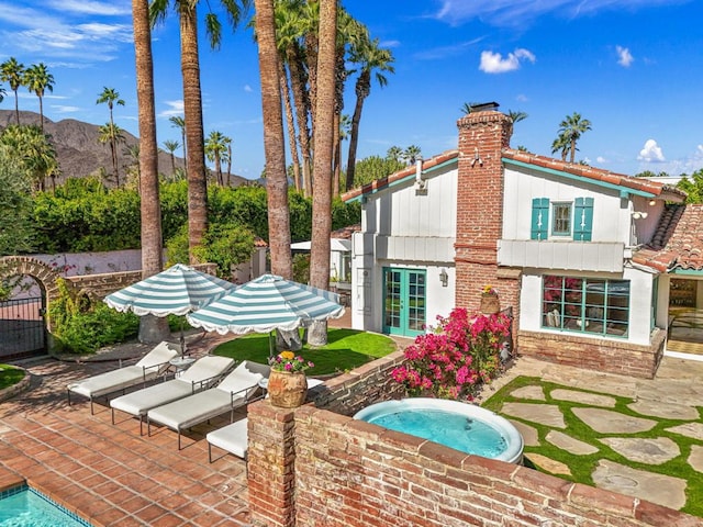 rear view of house featuring a mountain view, a patio, and a hot tub