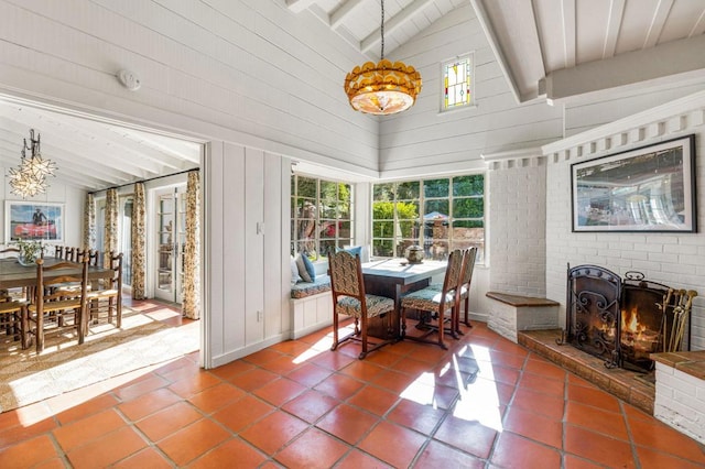 sunroom with vaulted ceiling with beams, a wealth of natural light, and a fireplace