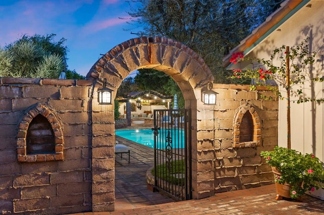 pool at dusk featuring a patio