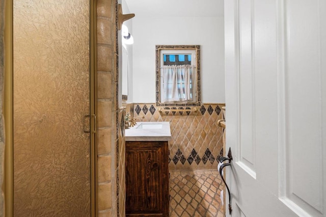 bathroom featuring vanity, a shower with shower door, and tile walls