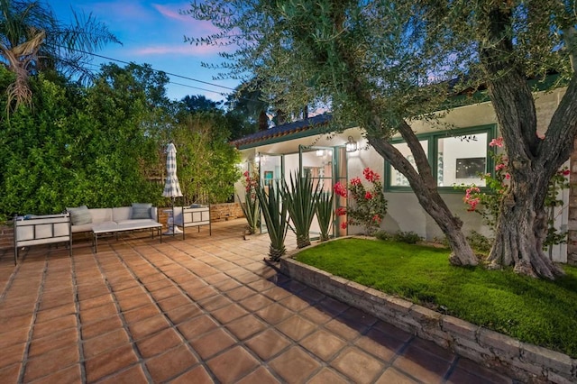 patio terrace at dusk with a lawn and outdoor lounge area