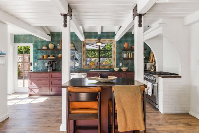 dining area with hardwood / wood-style floors, beamed ceiling, and sink