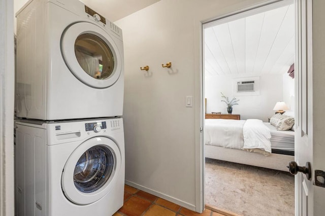 laundry room featuring a wall mounted air conditioner, dark tile patterned flooring, and stacked washer and clothes dryer