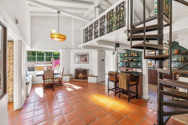 interior space featuring a brick fireplace, high vaulted ceiling, and beam ceiling