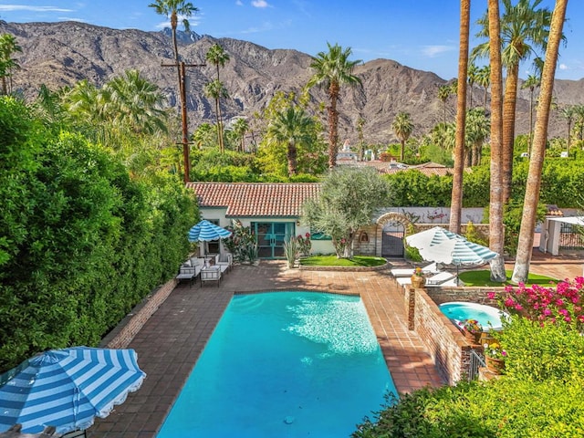 view of pool featuring a mountain view, an in ground hot tub, and a patio