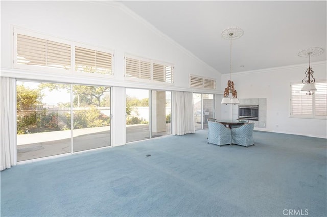 unfurnished living room with carpet flooring, a tiled fireplace, crown molding, and high vaulted ceiling