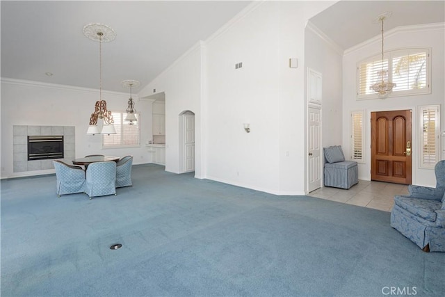 living room featuring a towering ceiling, light colored carpet, and crown molding