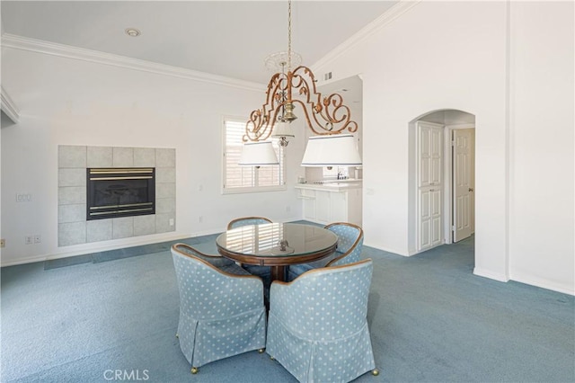 carpeted dining area featuring a fireplace, high vaulted ceiling, and ornamental molding