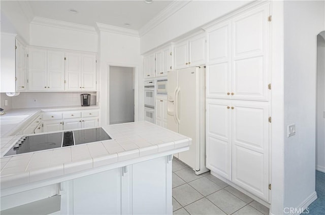 kitchen with tile countertops, white cabinetry, light tile patterned flooring, and white appliances