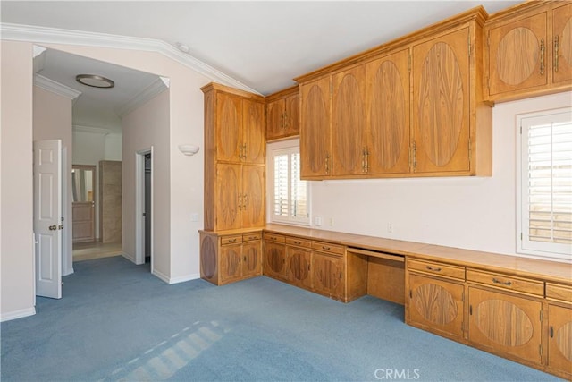 unfurnished office featuring built in desk, ornamental molding, a wealth of natural light, and vaulted ceiling