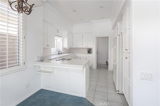 kitchen with white refrigerator, sink, kitchen peninsula, tile counters, and white cabinetry