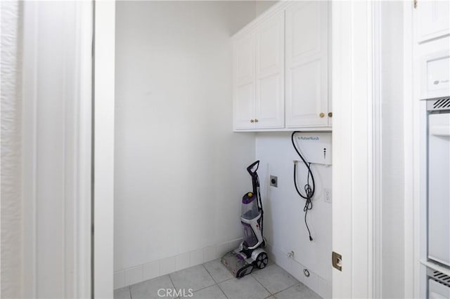 laundry area featuring cabinets, electric dryer hookup, and light tile patterned flooring