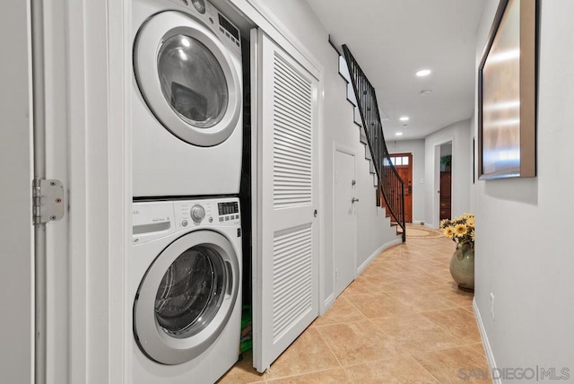 laundry area with light tile patterned flooring and stacked washer / dryer