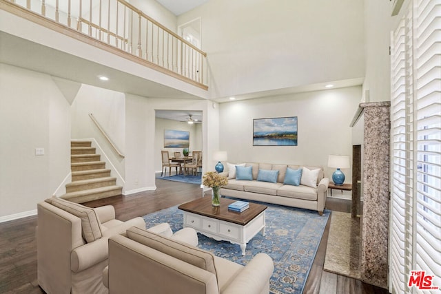 living room with a towering ceiling, a healthy amount of sunlight, and dark hardwood / wood-style floors