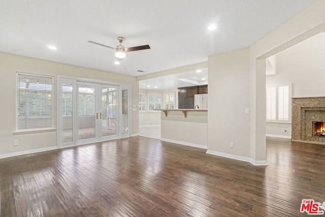 unfurnished living room featuring dark hardwood / wood-style floors, ceiling fan, a high end fireplace, and french doors