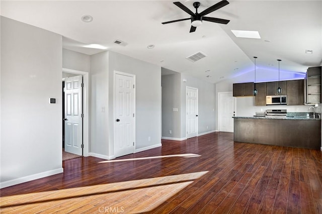 kitchen featuring dark brown cabinetry, appliances with stainless steel finishes, dark hardwood / wood-style flooring, ceiling fan, and vaulted ceiling with skylight