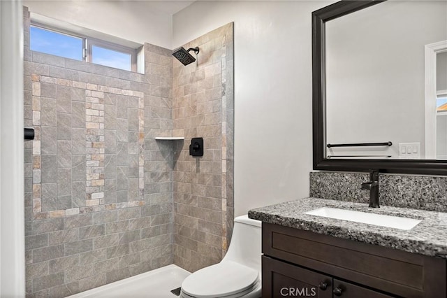 bathroom with vanity, toilet, and a tile shower