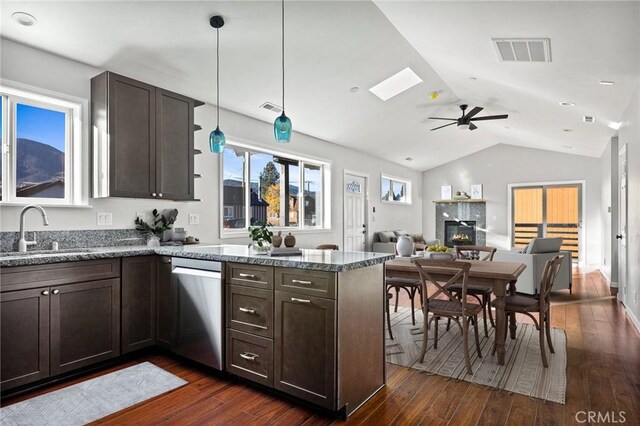 kitchen featuring sink, dark wood-type flooring, hanging light fixtures, stainless steel dishwasher, and vaulted ceiling with skylight