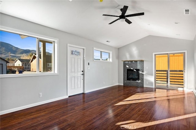 unfurnished living room with vaulted ceiling, a mountain view, dark wood-type flooring, and ceiling fan