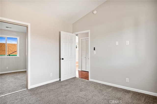 unfurnished bedroom featuring vaulted ceiling and dark colored carpet