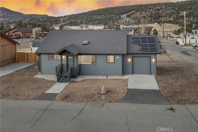 view of front facade featuring a garage, a mountain view, and solar panels