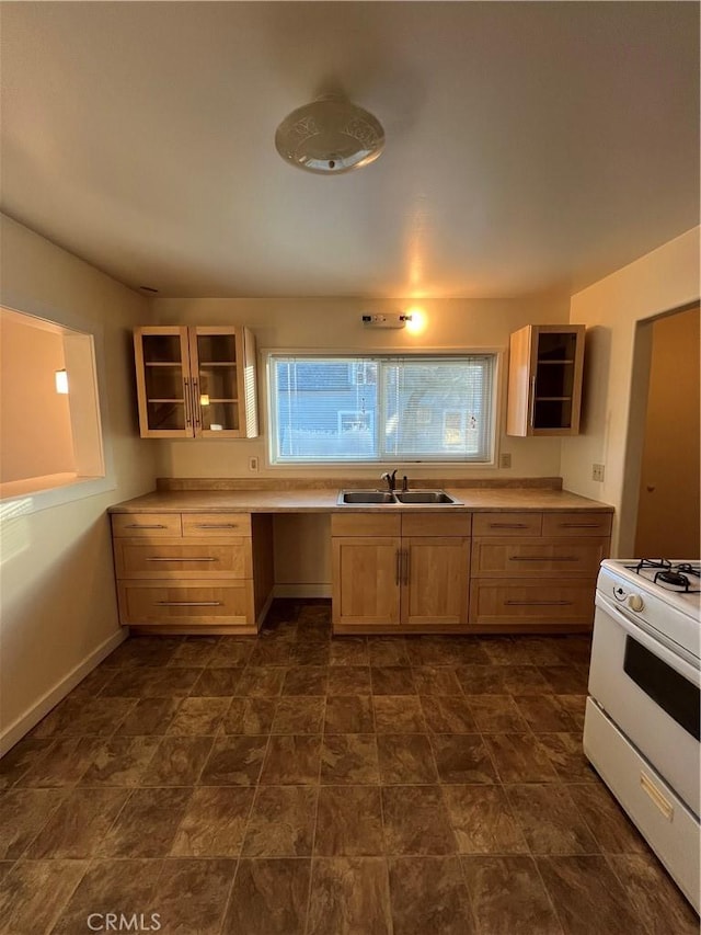 kitchen with sink, light brown cabinetry, white gas range oven, and built in desk