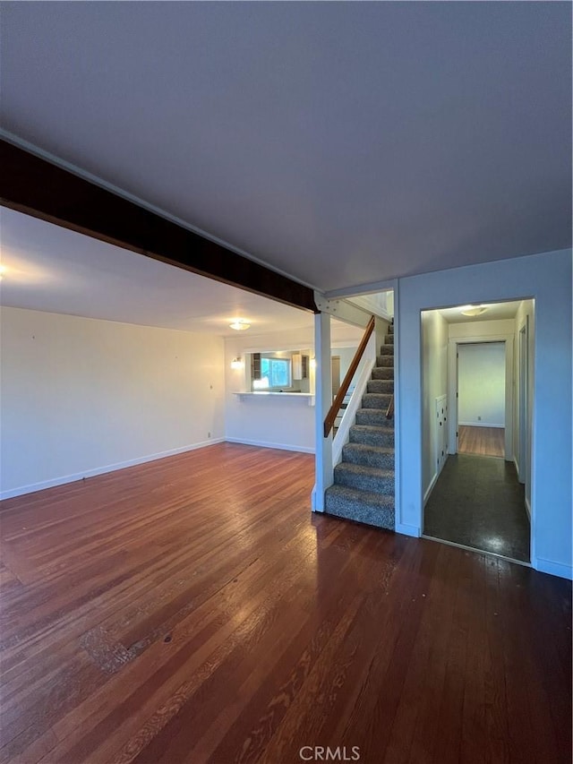 unfurnished living room featuring beam ceiling and dark hardwood / wood-style floors