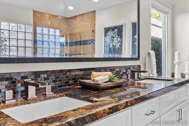 bathroom with decorative backsplash, vanity, and an enclosed shower