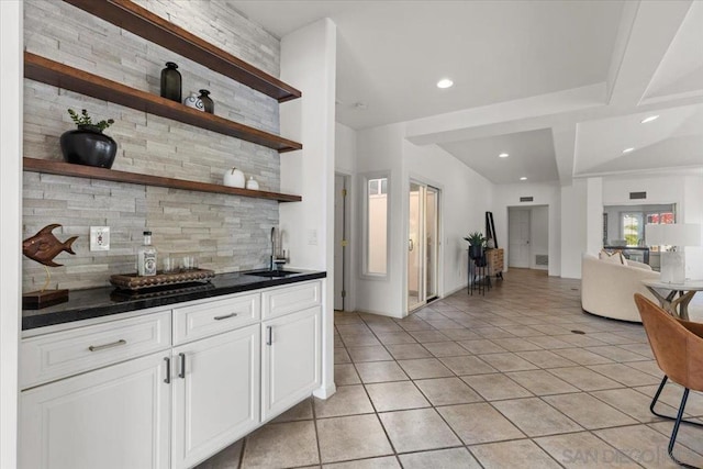 kitchen featuring tasteful backsplash, white cabinetry, sink, and light tile patterned floors