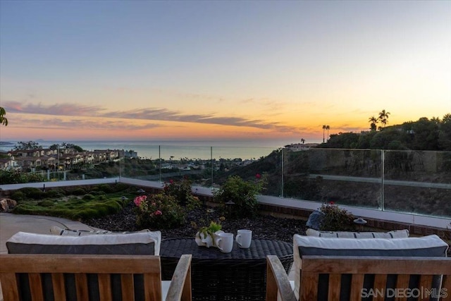 patio terrace at dusk featuring a water view