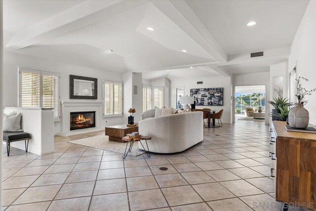 living room with vaulted ceiling with beams and light tile patterned flooring