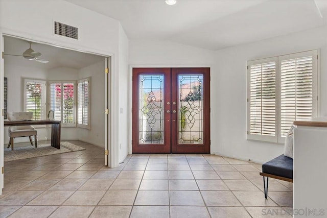 foyer featuring french doors, lofted ceiling, light tile patterned floors, and a healthy amount of sunlight