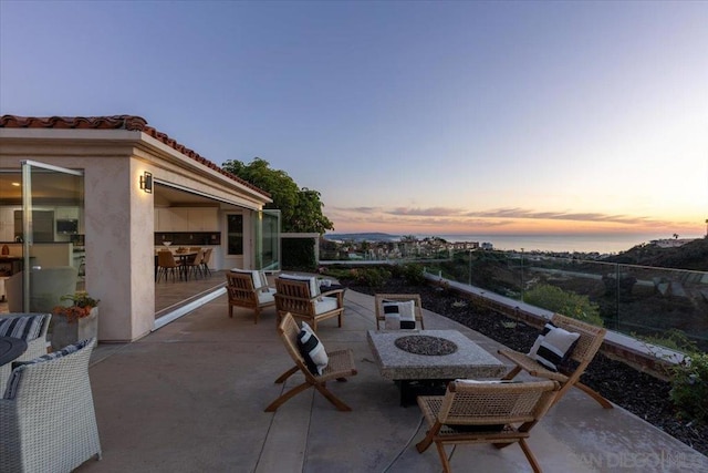 patio terrace at dusk featuring a fire pit and a water view