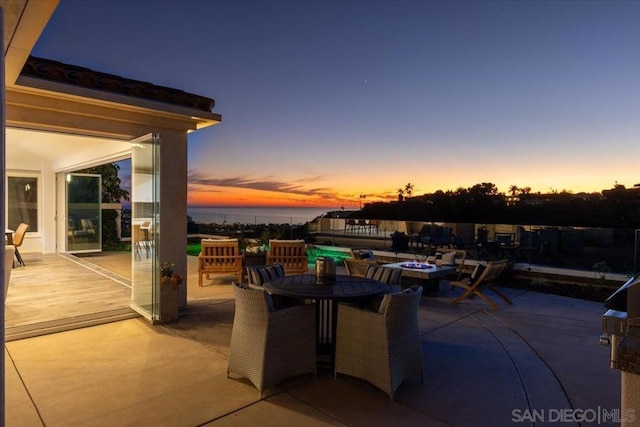 patio terrace at dusk featuring a water view