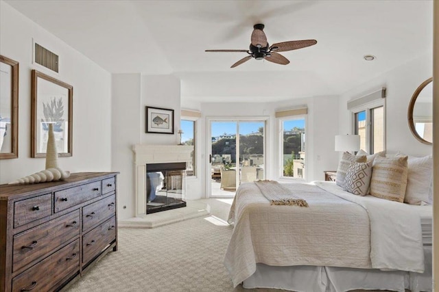 carpeted bedroom with a multi sided fireplace, ceiling fan, and access to exterior