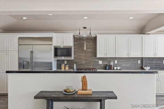 kitchen with built in appliances, lofted ceiling, white cabinetry, and hardwood / wood-style flooring