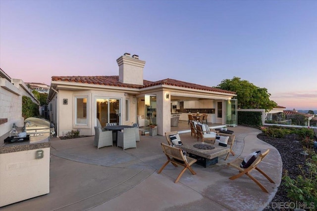 patio terrace at dusk with an outdoor kitchen and grilling area