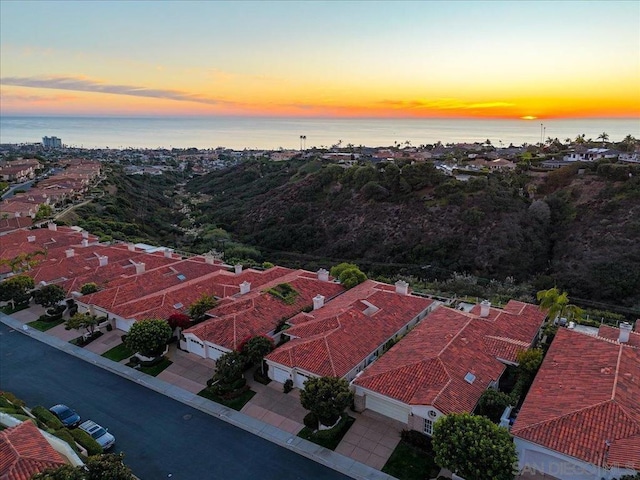 aerial view at dusk featuring a water view