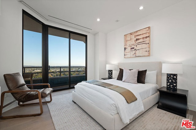 bedroom featuring access to exterior, light hardwood / wood-style flooring, and multiple windows