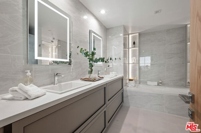 bathroom with decorative backsplash, vanity, tile patterned floors, and tile walls