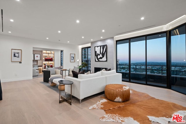 living room with floor to ceiling windows, a large fireplace, and light wood-type flooring