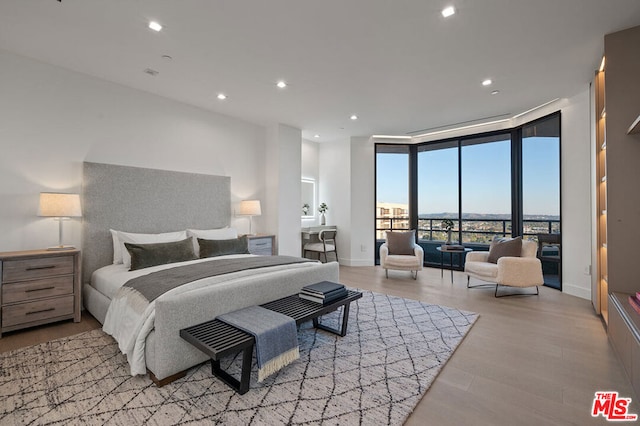 bedroom with access to exterior, light hardwood / wood-style floors, and a wall of windows