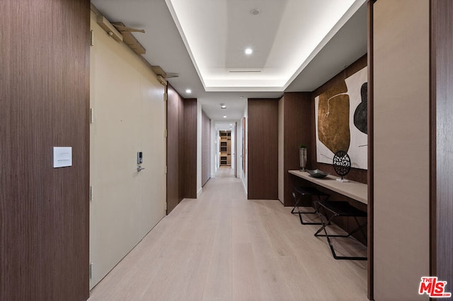 hall featuring a tray ceiling and light hardwood / wood-style floors