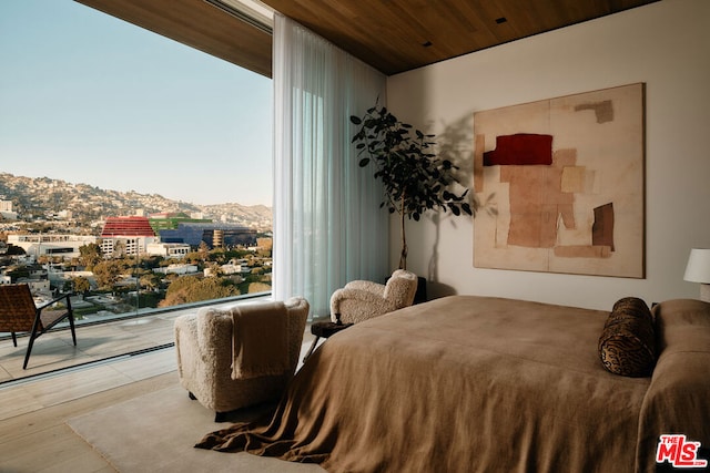 bedroom with a mountain view, light hardwood / wood-style floors, and wooden ceiling