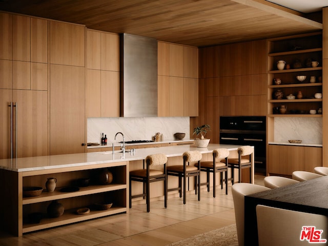 kitchen featuring a kitchen breakfast bar, light hardwood / wood-style flooring, built in features, a kitchen island, and wood ceiling