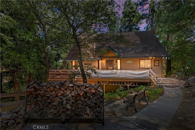 back house at dusk featuring a hot tub