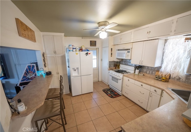 kitchen featuring backsplash, white cabinetry, light tile patterned floors, and white appliances