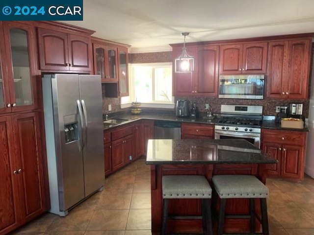 kitchen with decorative light fixtures, a kitchen island, stainless steel appliances, and tasteful backsplash