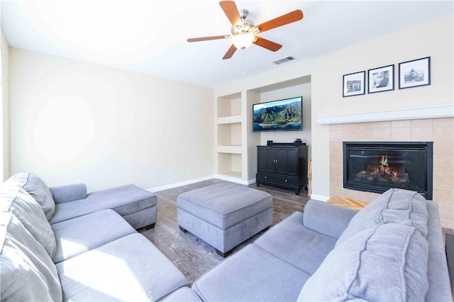 living room with built in shelves, ceiling fan, hardwood / wood-style floors, and a fireplace